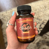 Hand holding a bottle of Happenstence Chaga supplement with a blurred background