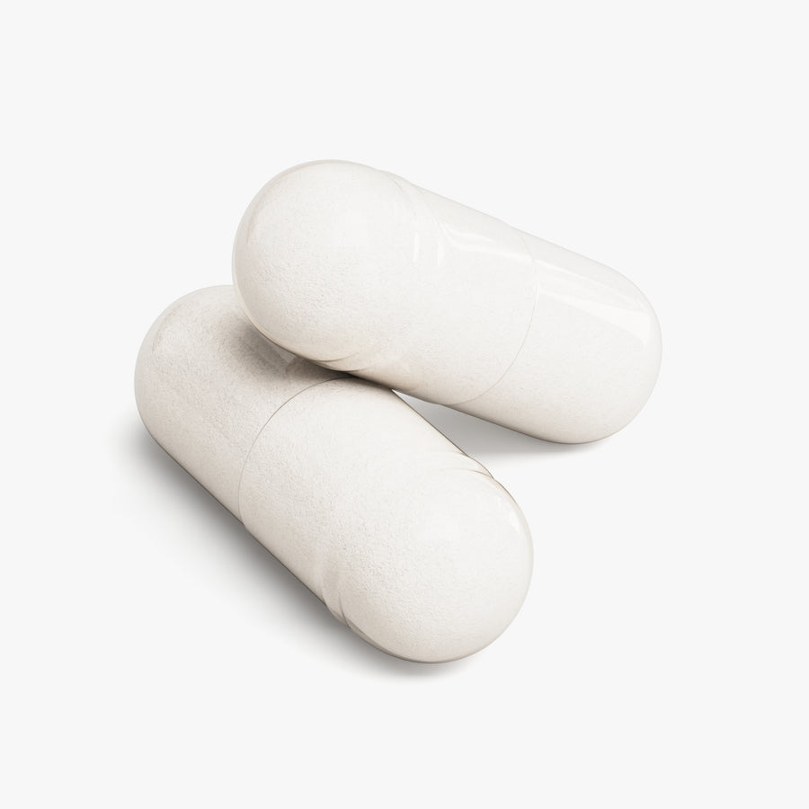 Two white magnesium capsules on a light gray background